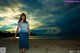 A woman standing on a sandy beach at sunset.