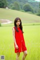 A woman in a red dress standing in a field.