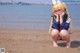 A woman in a bunny costume crouching on the beach.