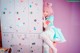 A woman with pink hair sitting in front of lockers.