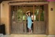 A woman in a blue dress standing in front of a wooden door.