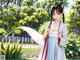 A woman in a white dress holding a sword in a park.