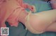 A woman in a pink shirt and white panties laying on a bed.