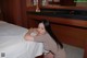 A woman leaning on a bed in a hotel room.