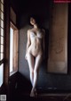 A naked woman standing in front of a window.